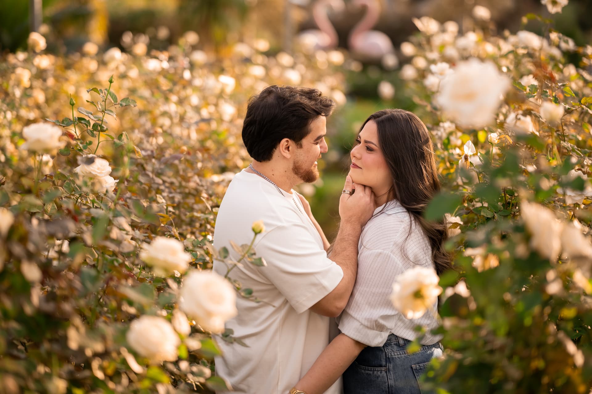 Monique e Thiago se olhando entre rosas brancas