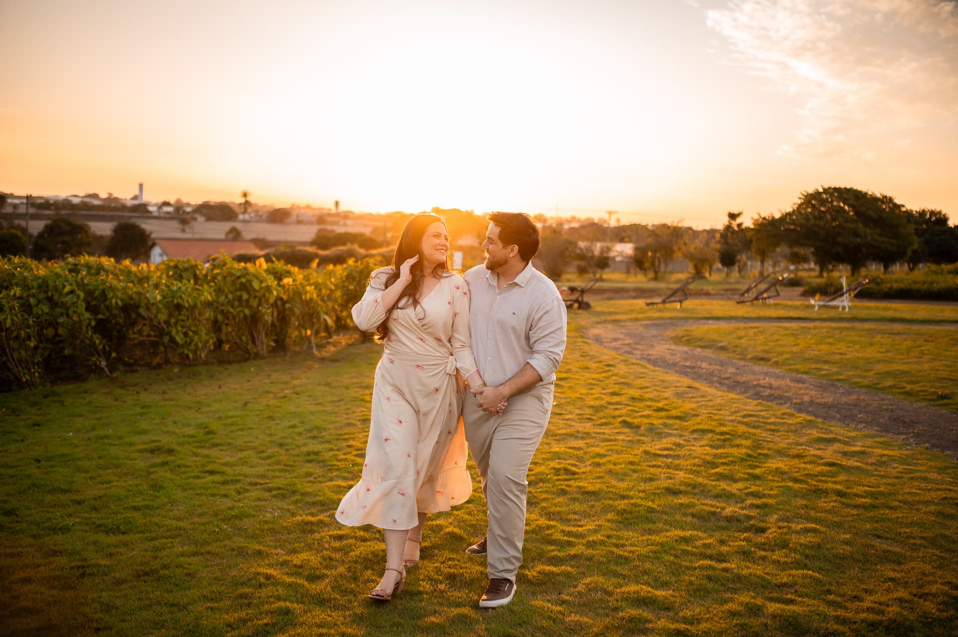 Monique e Thiago caminhando de mãos dadas ao pôr do sol