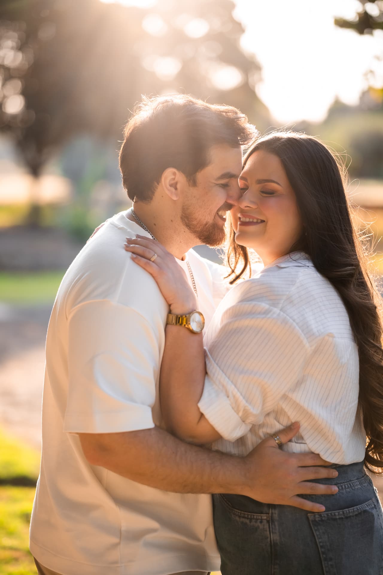 Monique e Thiago abraçados e sorrindo em um parque